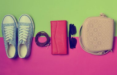 Kadın ayakkabı ve moda aksesuarları bir yeşil pembe pastel arka plan. Spor ayakkabı, çanta, çanta, kemer, güneş gözlüğü. İlkbahar Yaz koleksiyonu. Minimalizm eğilimini. Seyahat kavramı.