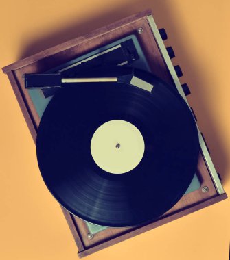 Pastel sarı bir arka plan üzerinde vinil plaka ile Vintage Vinil pikap. Eğlence 70 lerin. Müzik dinlemek. Üstten görünüm.