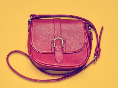 Kırmızı deri çanta sarı bir arka plan üzerinde uzun bir kayış üzerinde. Bayan aksesuarlar. Üstten görünüm.