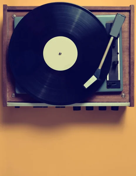 Vintage vinyl turntable with vinyl plate on a yellow pastel background. Entertainment 70s. Listen to music. Top view.
