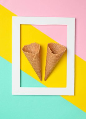 Pastel renkli bir arka plan üzerinde beyaz bir dikdörtgen çerçeve içinde iki boş gözleme boynuz. Minimalist eğilim, top vie