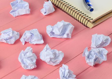 Kağıt topları, defter bir kalem üzerinde pembe ahşap bir masa iş concep ile