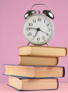Çalar saat üstünde pembe adam kitap yığınları