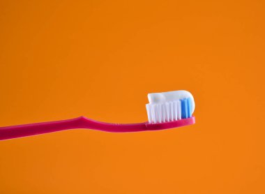 Turuncu bir açık renkli bir pembe diş fırçası yakın çekim üzerinde diş macunu