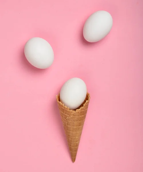 White chicken eggs in a waffle horn on a pink background, top view, flat lay, minimalist tren