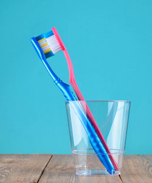 Duas Escovas Dentes Copo Plástico Transparente Banheiro Fundo Azul Minimalis — Fotografia de Stock