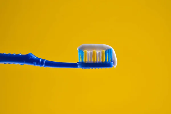 Toothpaste Blue Toothbrush Close Yellow Light Background — Stock Photo, Image