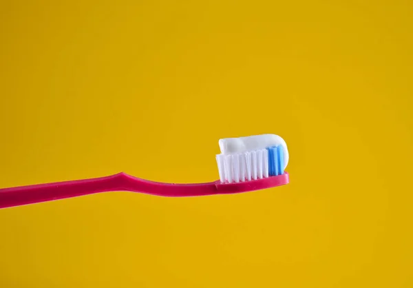 Pasta Dentes Uma Escova Dentes Rosa Close Fundo Luz Amarela — Fotografia de Stock