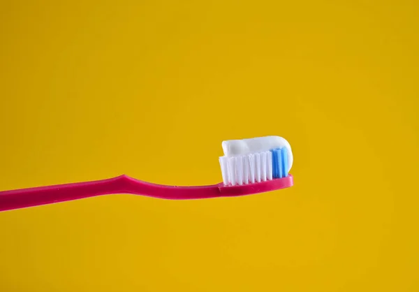 Pasta Dientes Sobre Cepillo Dientes Rosa Cerca Sobre Fondo Amarillo — Foto de Stock