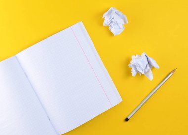 Sarı zemin üzerine üstten görünüm defter kalem ve beyaz buruşuk Kağıt topu ile. Hiçbir fikir, eğitim, mimari konsepti