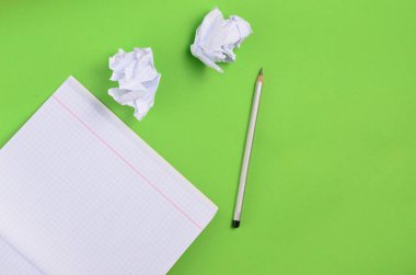 Yeşil zemin üzerine üstten görünüm defter kalem ve beyaz buruşuk Kağıt topu ile. Hiçbir fikir, eğitim, mimari konsepti