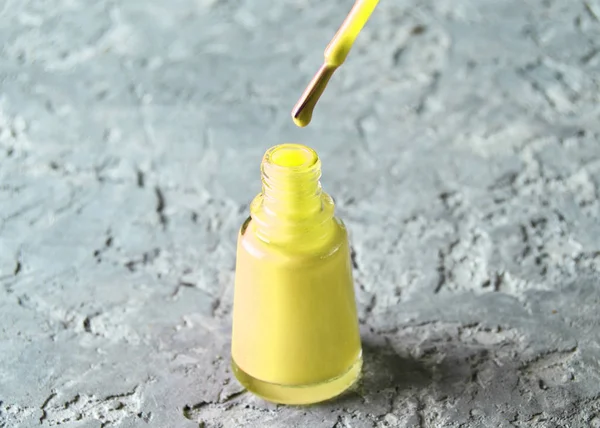 Yellow nail polish close-up on gray concret