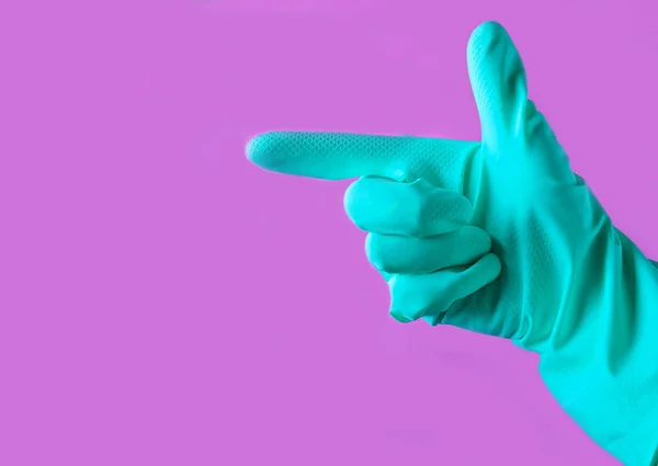 Hand with yellow rubber glove is pointing in the side on a blue pastel background, cleaning concept, copy spac