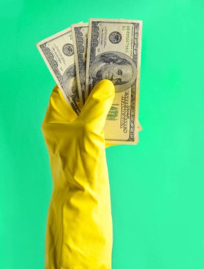Temizlik için sarı lastik eldiven ile erkekler el yüz dolarlık banknot mavi bir arka plan üzerinde tutun. Wor için ödeme