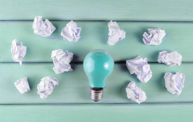 Renkli bir akkor ampul ve buruşuk beyaz kağıt topları mor bir ahşap masa üzerinde. İdeolojik kavramı, top vie