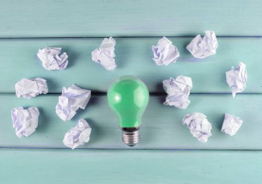 Renkli bir akkor ampul ve buruşuk beyaz kağıt topları mor bir ahşap masa üzerinde. İdeolojik kavramı, top vie