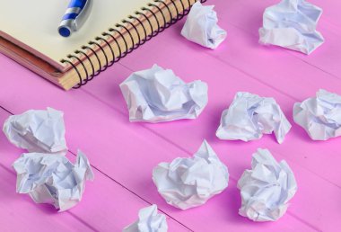 Kağıt topları, defter bir kalem üzerinde pembe ahşap bir masa iş concep ile