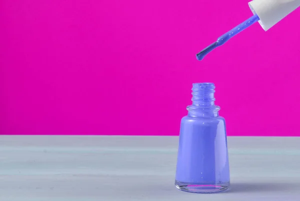 Open bottle of pink nail polish on a yellow background, copy space