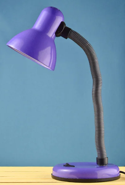 Table lamp on a table isolated against a blue wall backgroun