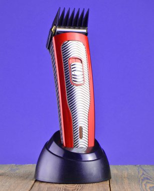 Mavi duvar adam karşı ahşap bir masa üzerinde bir şarj istasyonu kablosuz clipper bir meme ile standları