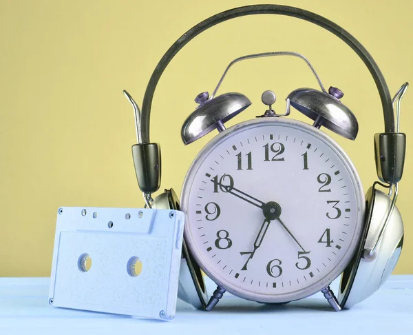 ヘッドフォンとオーディオ カセット コピー Spac パステル背景に木製のテーブルの上のレトロな目覚まし時計 — ストック写真