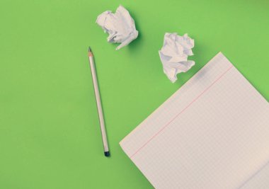 Yeşil zemin üzerine üstten görünüm defter kalem ve beyaz buruşuk Kağıt topu ile. Hiçbir fikir, eğitim, mimari konsepti