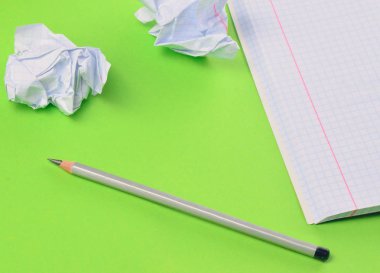 Defter kalem ve beyaz buruşuk Kağıt topu yeşil arka plan ile. Hiçbir fikir, eğitim, mimari konsepti