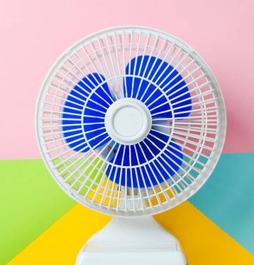 Pastel renkli arka plan üzerinde mavi panjurlar ile beyaz plastik fan. Üstten görünüm.