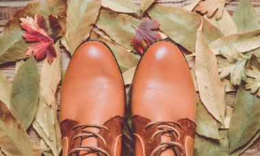 Kadınlar boots kahverengi deri sarı düşen yapraklar arka planı.
