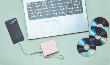 Laptop, smartphone, güç banka, yeşil bir arka plan üzerinde Cd sürücüleri. Dijital medya, becerikli alet.
