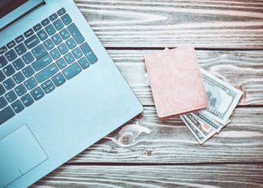 Laptop ve çanta ahşap bir masa üzerinde para ile. Internet, online iş kavramı freelancing. Üstten görünüm.