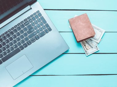Laptop ve çanta turkuaz ahşap bir masa üzerinde para ile. Internet, online iş kavramı freelancing. Üstten Görünüm.