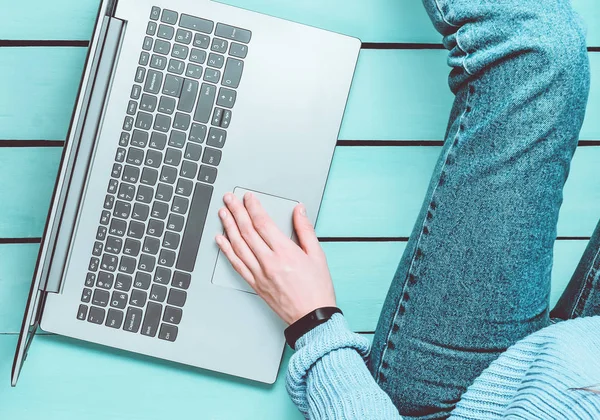 一个现代的女孩坐在蓝色的木地板上 并使用笔记本电脑 自由职业者的概念 工作空间 顶部视图 — 图库照片