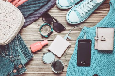 Kadın moda aksesuarları, Ayakkabı, giyim ve ahşap arka plan üzerinde modern araçlar. Kot pantolon, çanta, Ayakkabı, smartphone, akıllı bilezik, güç banka, kozmetik, güneş gözlüğü, eşarp. Üstten Görünüm. Düz yatıyordu.