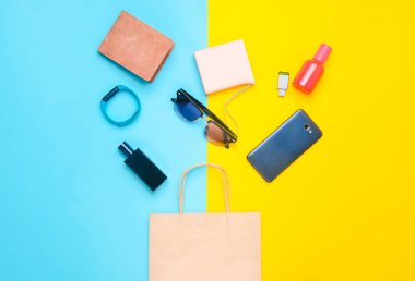 Kağıt torba ve becerikli alet ve aksesuarları renkli bir arka plan üzerinde birçok alışveriş: güneş gözlüğü, smartphone, akıllı bilezik, powel banka, usb flash sürücü, m-cüzdan. Tüketici kavramı. Üstten Görünüm.