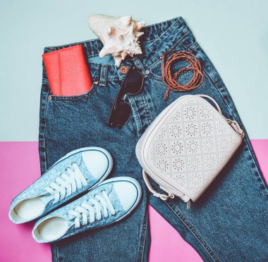 Bayan aksesuarlar klasik kot ile abartılı bir bel yalan. Spor ayakkabı, çanta, çanta, kemer pembe yeşil arka plan üzerinde. Üstten görünüm. Seyahat kavramı.