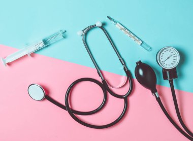 Tıbbi malzeme renkli kağıt arka plan üzerinde. Stetoskop, şırınga, termometre, tonometer. Üstten görünüm, düz yatıyordu.