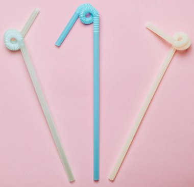 Pastel pembe bir arka plan üzerinde renkli kokteyl tüpler. Üstten görünüm. Uzay kopyalayın. Minimalist eğilim.