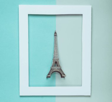 Pastel renkli bir arka plan üzerinde beyaz bir çerçeve Eyfel Kulesi Hatıra heykelciği. Minimalist eğilim. Üstten görünüm.