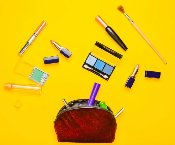 Cosmetic bag and women\'s cosmetics for make-up layout on a yellow background. Cosmetic shadows, make-up brush, eyeshadow lipstick, perfume bottle. Flat lay, top view. Copy space.