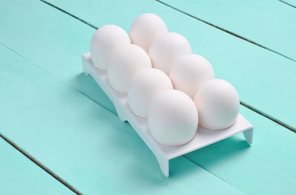 Plastic tray with white eggs on a pastel blue wooden table, minimalism tren