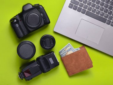 Ekipman fotoğrafçı, dizüstü bilgisayar, çanta dolar üzerinde yeşil bir arka plan ile. Serbest kavramı, fotoğrafçının çalışmaları, nesneleri, üstten görünüm, düz la
