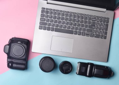 Ekipman fotoğrafçı, dizüstü bilgisayar, çanta dolar, pastel pembe mavi arka plan ile. Serbest kavramı, fotoğrafçının çalışmaları, nesneleri, üstten görünüm, düz la