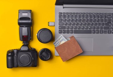 Ekipman fotoğrafçı, dizüstü bilgisayar, çanta dolar üzerinde sarı bir arka plan ile. Serbest kavramı, fotoğrafçının çalışmaları, nesneleri, üstten görünüm, düz la
