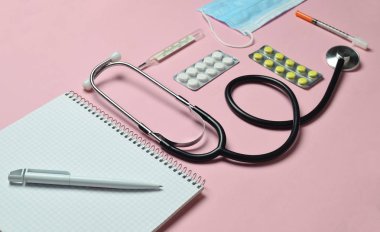 Tıbbi ekipman üzerinde bir pastel pembe. Kabarcıklar hapları, Not defteri, stetoskop, termometre. Tıbbi kavramı, üstten görünüm, düz yatıyordu styl