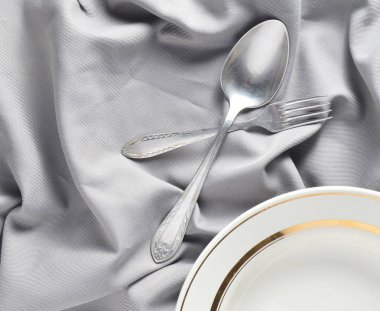Kaşık, çatal, plaka üzerinde gri bir ipek masa örtüsü. Romantik bir akşam yemeği. Üstten görünüm