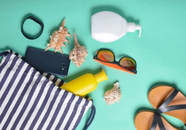 Plaj çantası ve aksesuarları pastel mavi arka plan üzerinde plaj düzendeki rahatlamak için. Deniz, yaz saati Resort'ta kavramı. Üstten görünüm, düz yatıyordu, minimalis