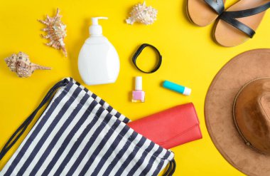 Plaj çantası ve plaj düzendeki sarı pastel arka plan üzerinde rahatlatıcı için aksesuarlar. Deniz, yaz saati Resort'ta kavramı. Üstten görünüm, düz yatıyordu, minimalis