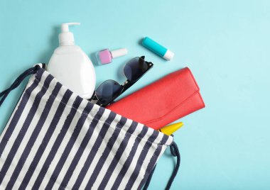 Plaj çantası ve aksesuarları pastel mavi arka plan üzerinde plaj düzendeki rahatlamak için. Deniz, yaz saati Resort'ta kavramı. Üstten görünüm, düz yatıyordu, Minimalizm, kopya girintili