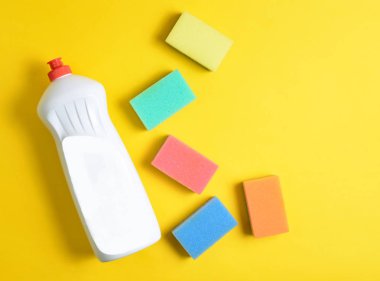 Bulaşık deterjanı, plastik şişe sünger sarı pastel arka plan, üstten görünüm, düz lay, minimalis